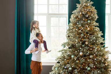Mutlu baba ve küçük kızı evdeki Noel ağacını süslüyorlar..