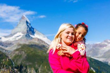 Dağ gezisi. Bir dağ gölünün arka planında iki mutlu kız ve arka planda dağlar.