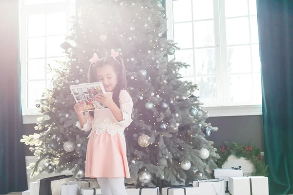 Klein Meisje Zoek Fotoboek Voorkant Van Kerstboom — Stockfoto