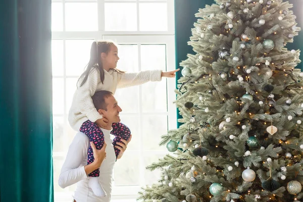 幸せな若い父親と娘がクリスマスツリーを持って家にいます — ストック写真