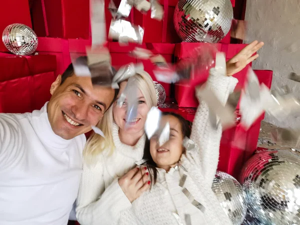 Christmas. Family. Technology. View on the smartphone. Dad, mom and daughter looking at camera and smiling while doing selfie