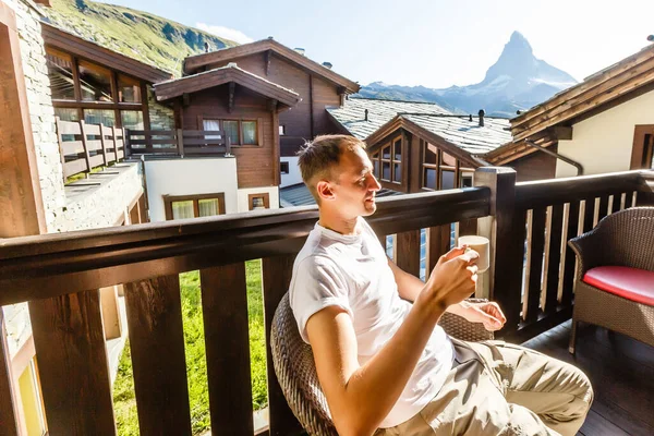 A young man in the morning looks from the hotel balcony with a view of the mountains. Mountain views at the hotel resort