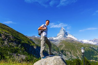 Matterhorn 'un önünde bir adam Matterhorn' a doğru yürüyor.