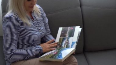 Kapat. Bir kadın, bahçedeki bir aile fotoğraf çekiminden fotoğraf defterini karıştırıyor. Güzel ve uygun fotoğraf deposu. Önemli bir dönemin anısı.