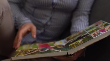 Kapat. Bir kadın, bahçedeki bir aile fotoğraf çekiminden fotoğraf defterini karıştırıyor. Güzel ve uygun fotoğraf deposu. Önemli bir dönemin anısı.
