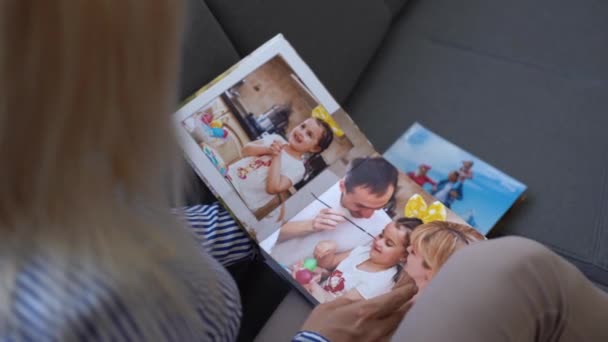 Fecha. uma mulher vira um livro de fotos de uma sessão de fotos de família no jardim. armazenamento bonito e conveniente de fotos. memória de um período importante. — Vídeo de Stock