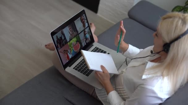 Online Groep Video Call Conferentie van het Werk Team van Binnenlandse Zaken. Vrouw in hoofdtelefoon praat met mensen op Video Chat met behulp van laptop. Zelfisolatie bij COVID-19 Pandemie. 4K Bovenaanzicht Medium Orbit Shot — Stockvideo