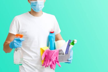 Adam apartman temizliği yapıyor. Enfeksiyon önleme ve salgının kontrolü. Koruyucu eldivenler ve maske. mavi arkaplan