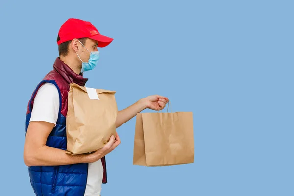 マスクと手袋の配達人は 顧客の家に新鮮な食べ物をもたらします 家にいて オンラインショッピングのコンセプト 青の背景 — ストック写真