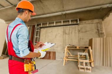 İnşaat arkaplanı üzerinde diy araç kemeri olan bir işçi