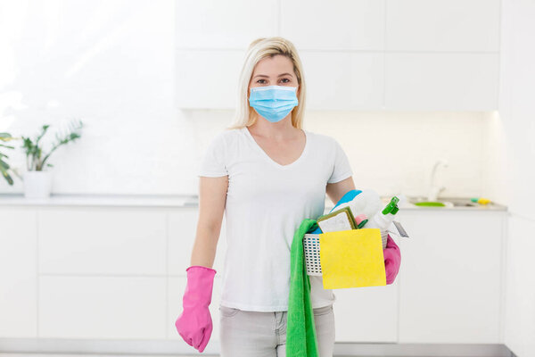 Красивая молодая женщина делает уборку дома. Девушка стирает пыль. Женщина в защитных перчатках и маске вытирает пыль с помощью спрея и пыли во время уборки своего дома, крупным планом