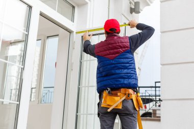 Bir işçi evin ön cephesine bej kaplama paneller yerleştirir