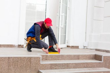 Bir işçi evin ön cephesine bej kaplama paneller yerleştirir