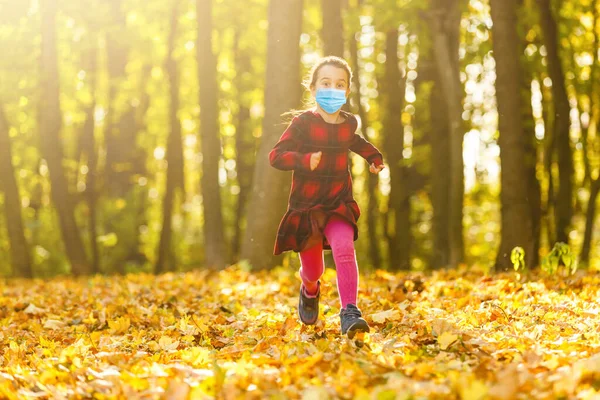 Mała Dziewczynka Masce Medycznej Zapobiega Zanieczyszczeniu Spadających Liści Parku — Zdjęcie stockowe