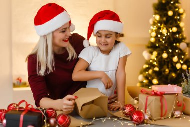 Mutlu Noeller ve mutlu tatiller. Bir anne ve kız Noel hediyeleri hazırlar. Mücevherler, hediyeler, Noel süslü şekerler Noel aile gelenekleri..