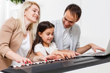 Mutlu aile, anne, baba ve kız evde piyano çalıyor, aile ilişkisi kavramı. müzik okulu ve müzik ailesi.