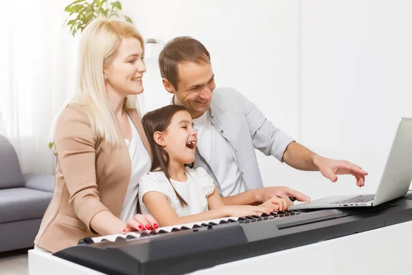 family plays the digital piano at home, learning online, family rest during quarantine, self-isolation, online education concept. support for loved ones concept