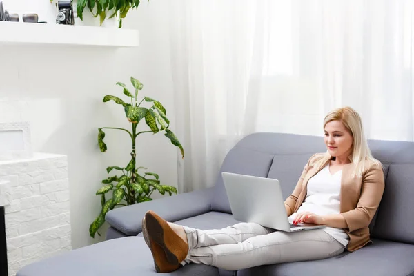 Portrait of happy skilled middle aged woman life coach, business consultant, psychologist or medical advisor smiling joyfully at camera, working on laptop, enjoying her job, helping people online