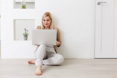 Ticari kadın. Genç bir kadın online alışveriş için bilgisayar kullanıyor, yerde oturuyor.