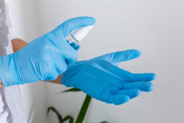 Arka planda antiseptik el dezenfektanı tutan plastik cerrahi eldivenler. Alkol dezenfektanları ya da el hijyen koronası virüsü koruması için jel. Covid-19 'a karşı antibakteriyel sıvı