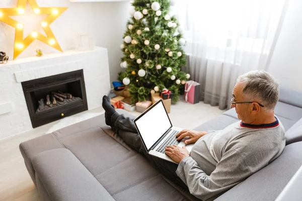 A senior man sitting by the fireplace at christmas