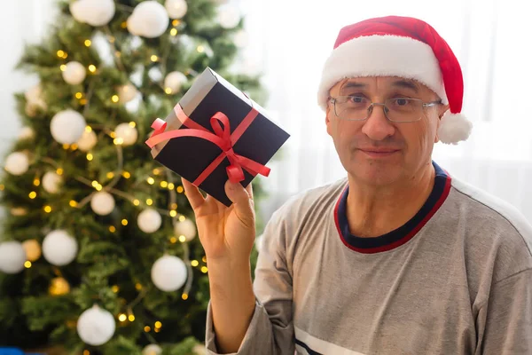 笑顔の肖像画白人の老人は家でクリスマスツリーの背景に座って — ストック写真