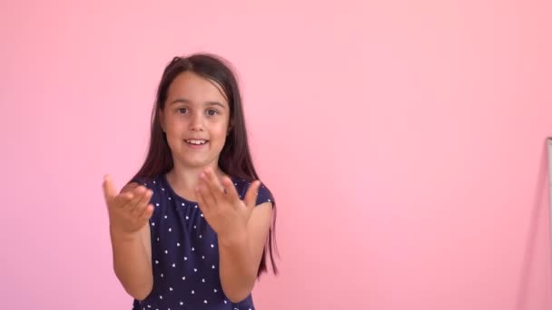 Niña señala a la supuesta escritura en la pared de fondo rosa — Vídeo de stock