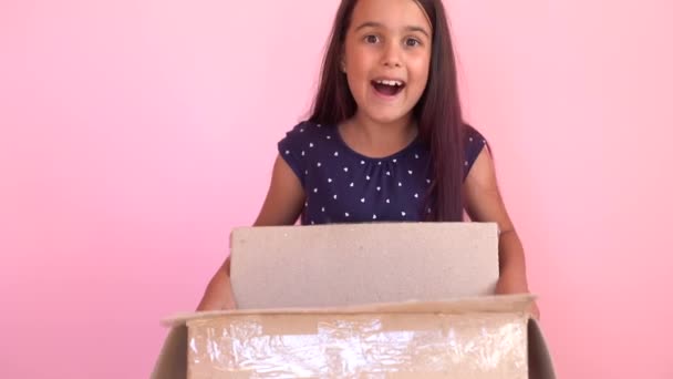 A girl looks in the box, is surprised and happy to receive a surprise. The child opened a box with a gift. — Stock Video