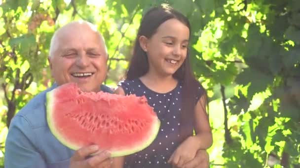 快乐的孩子吃西瓜。孩子们在户外吃水果。小女孩在花园里玩，咬着一片西瓜. — 图库视频影像