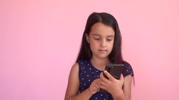 Χαριτωμένο κοριτσάκι προσχολικής ηλικίας χρησιμοποιώντας ένα smartphone, φαίνεται τηλέφωνο. Παίζει στο τηλέφωνο. Παιδική τεχνολογία εθισμός έννοια παιχνίδι — Αρχείο Βίντεο