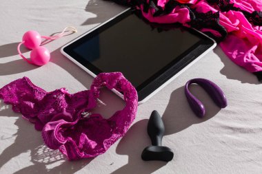 Tablet seks oyuncağı ve orgazm konsepti. Mor silikon bir vibratörün üzerinde yatıyordu.