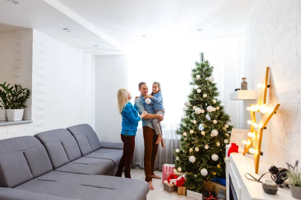 happy young family with one child holding christmas gift and smiling