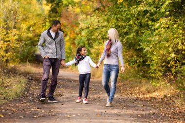 Mutlu bir aile Sonbahar parkında yürüyor