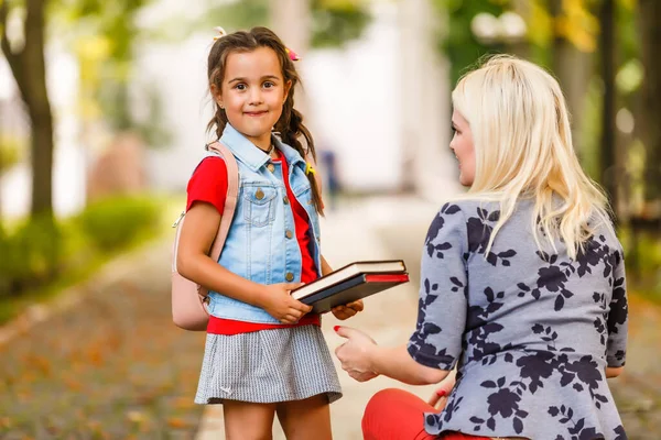 first day at school. mother leads a little child school girl in first grade