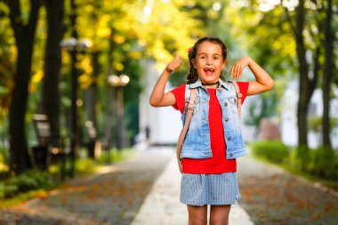 Sabahları küçük bir kız sıcak güneşin altında sırt çantasıyla okula gidiyor. Eğitim kavramı.