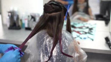 Güzel küçük bir kız. Çenesini ovalıyor. Güzellik salonunda boyayı seçiyor.