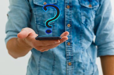 Akıllı telefonlu, soru işareti hologramı olan bir iş adamı siyah arkaplanda görünüyor.