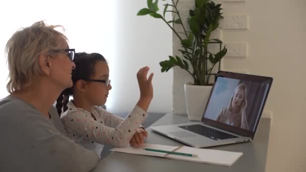 Ganska lågstadie flicka distansundervisning hemma. Fokuserade söt unge lyssna ljud lektion studerar vid bordet, gör läxor. Fjärrundervisning för barn om karantänbegreppet. — Stockvideo