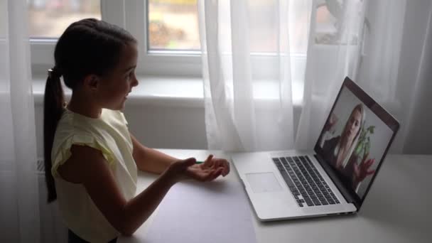 Pretty primary school girl distance learning at home. Focused cute kid listening audio lesson studying at table, doing homework. Children remote education on quarantine concept. — Stock Video