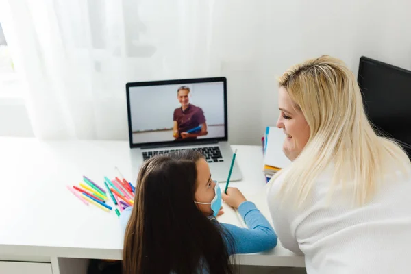 Digital technology education concept. little girl in a protective mask at distance home schooling, quarantine