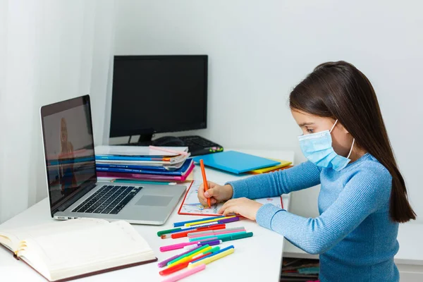 little girl in a protective mask at distance home schooling, quarantine