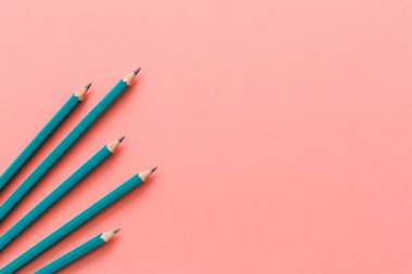 Tahta kalemlerin minimalist ve temiz gözüken pembe kağıtlara izole edilmiş makro fotoğraflarının üstten görünümü ile kopya alanı ile şablon.