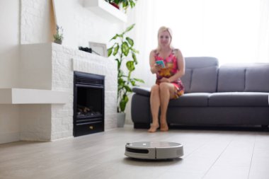 Temizlik konsepti: Kadın dinlenirken otomatik robot süpürge odayı temizler.