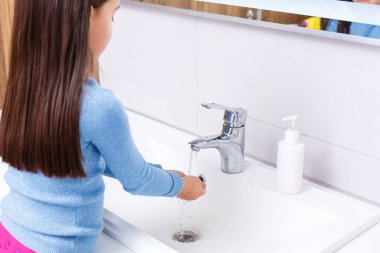 Küçük çocuk ellerini sabun ve suyla yıkıyor.