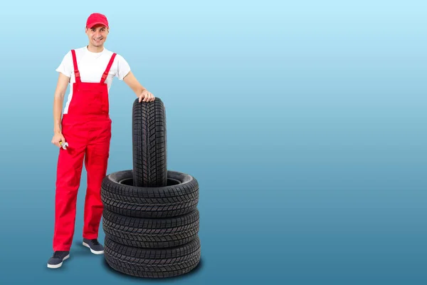 Car Mechanic Carrying Tire Blue Background Happy Man Smiling Amd — Stock Photo, Image
