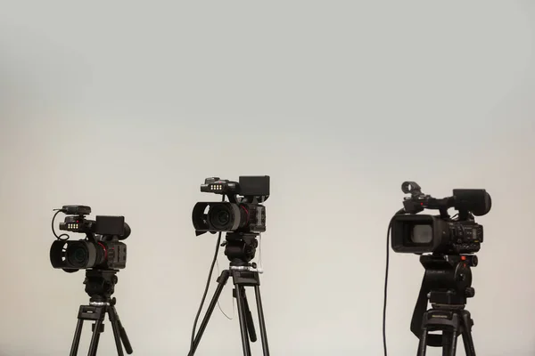 Professional camcorder, video camera on tripod, black silhouette on blue background