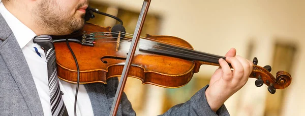 Playing violin, a musician plays vintage violin on a concert, close up