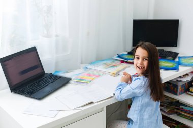 Eğitim ve okul konsepti - evde eğitim gören gülümseyen küçük kız öğrenci