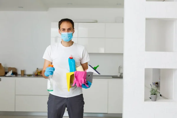 cleaning, health and hygiene concept - indian man wearing protective medical mask for protection from virus disease in gloves with detergent and mop at home