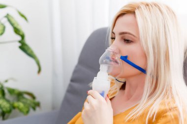 Astım ve solunum hastalıkları için nebulizör kullanan genç bir kadın.